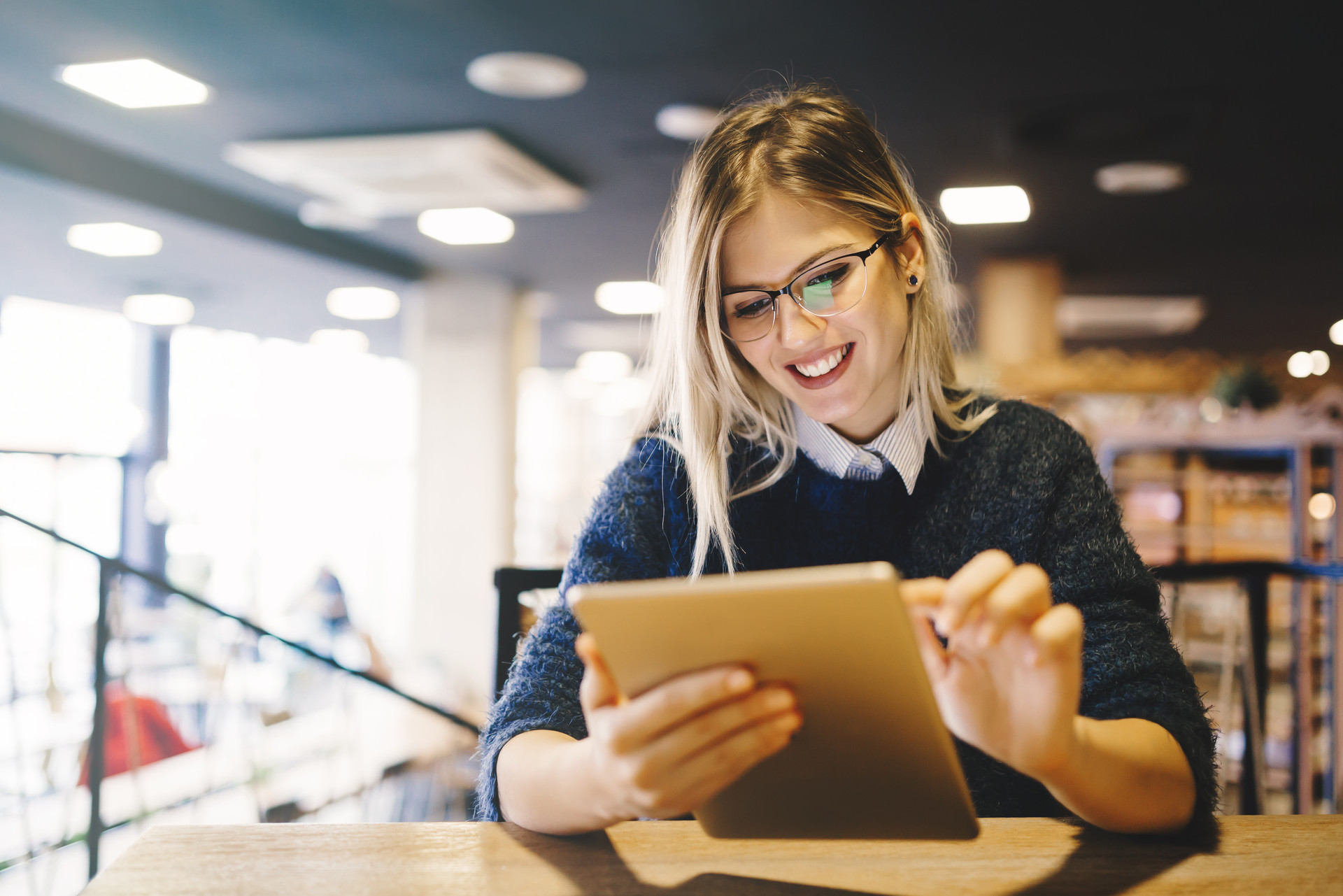 Junge Frau arbeitet mit ihrem Tablet an einem LMS und liest sich E-Learning Inhalte durch