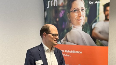 Stefan Medinger, der Geschäftsführer, steht vor einem Rollup-Banner mit Text und Bildern.