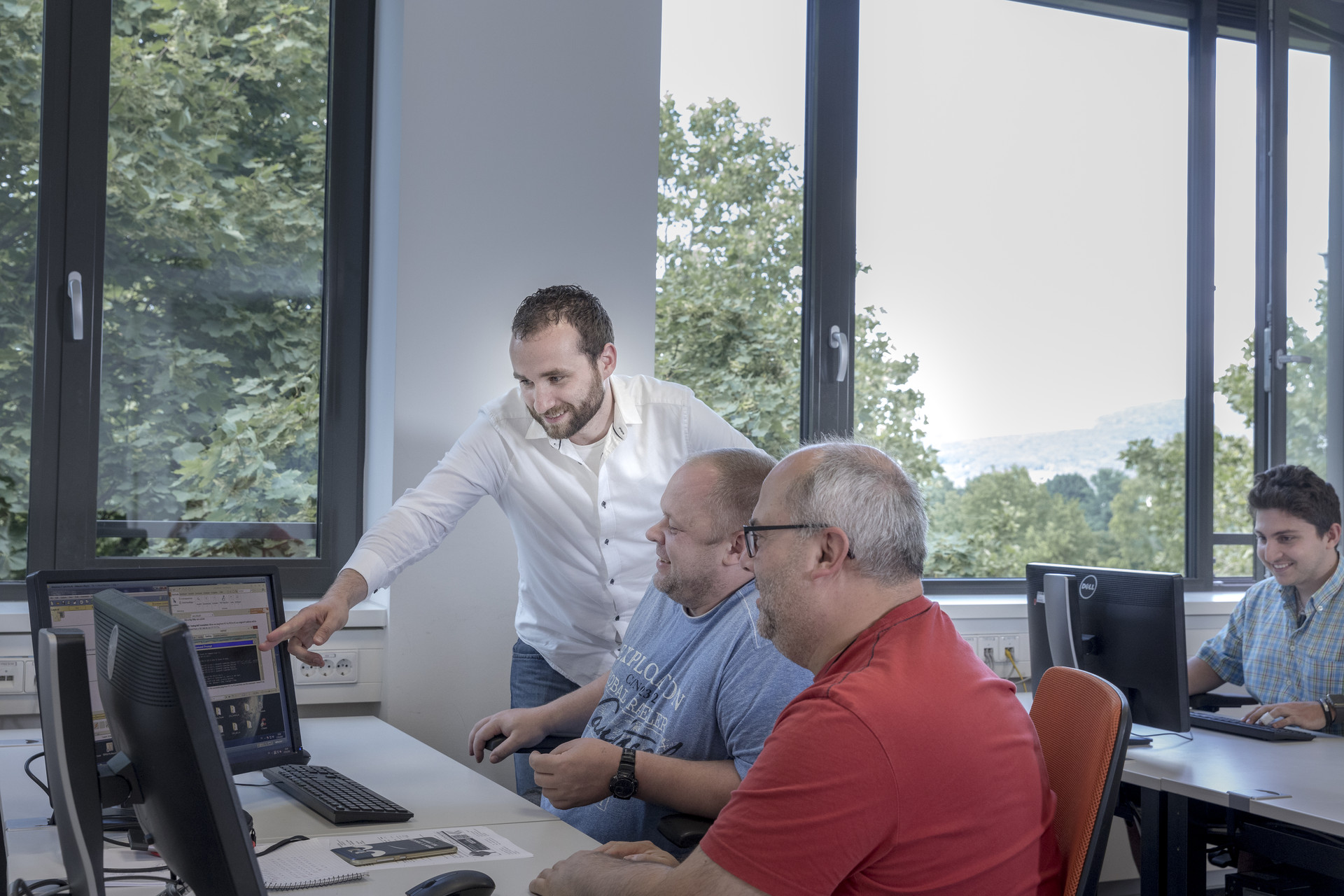 IT-Dozent erklärt etwas IT-Dozent erklärt zwei Teilnehmenden etwas am Bildschirm