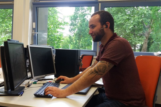 Foto: Die Lehrkraft sitzt am BFW Heidelberg vor ihren PCs mit der Online-Konferenz.