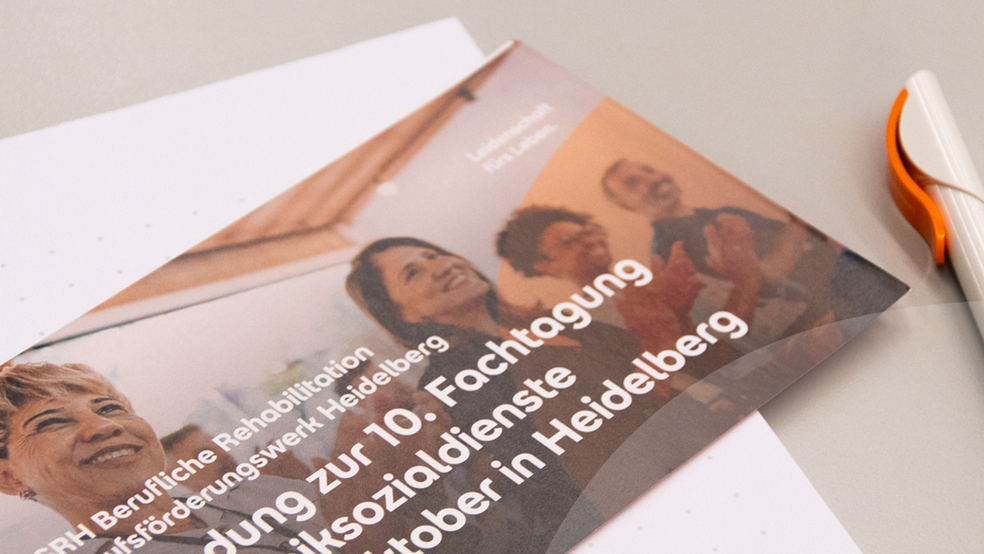 Ein Flyer mit dem Titel '10. Fachtagung der Kliniksozialdienste' liegt auf einem Schreibtisch