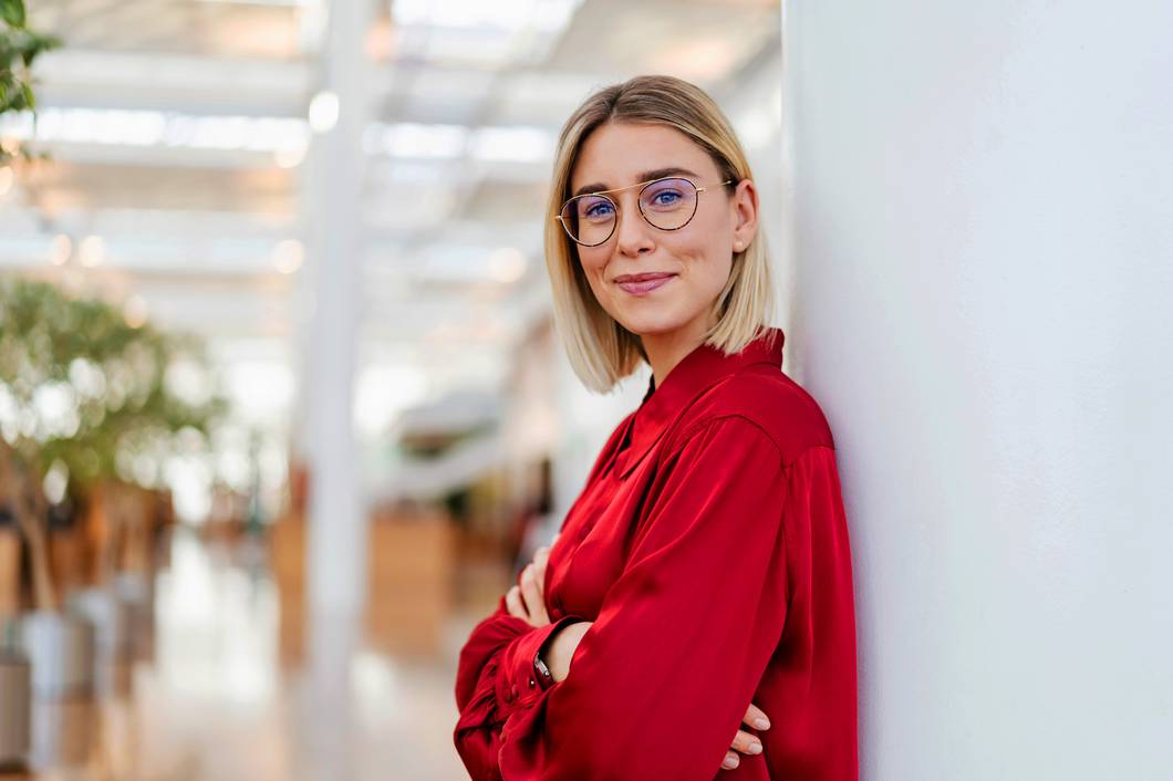 Frau ist mit Rücken an Türrahmen angelehnt und lächelt in die Kamera