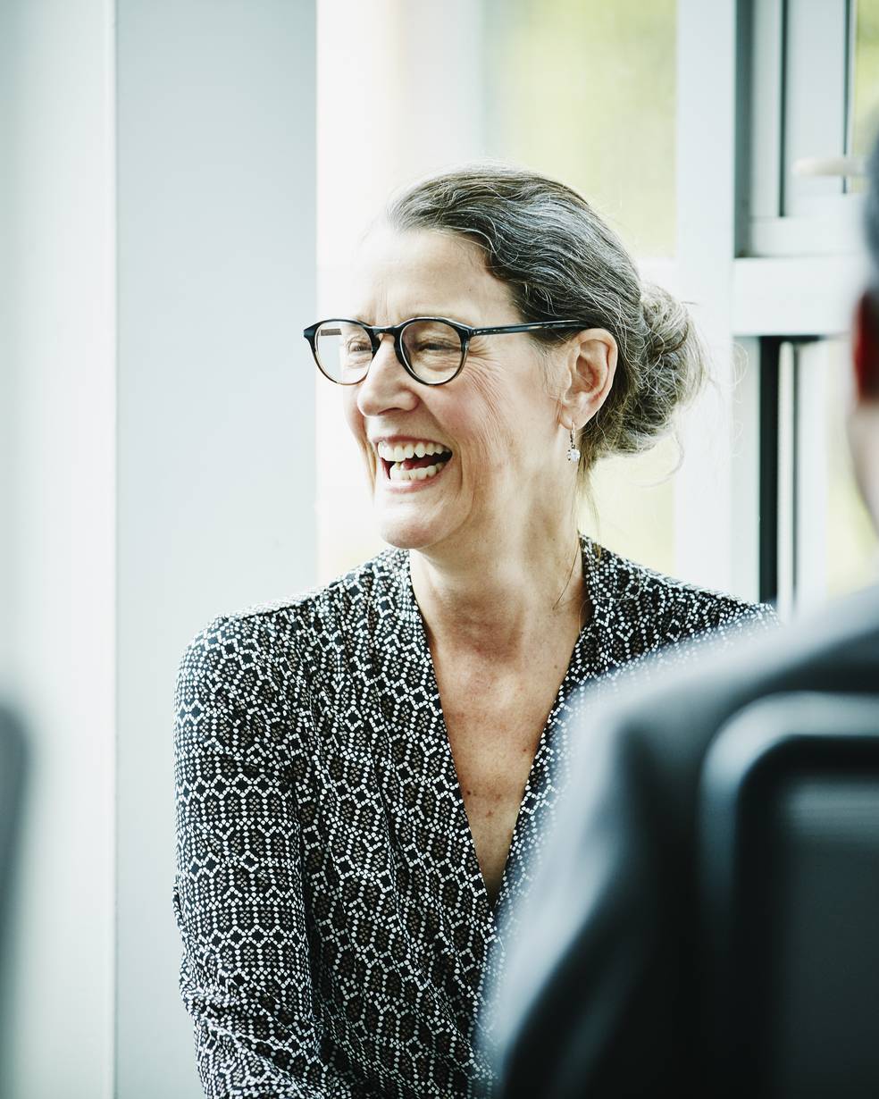 Eine Frau lacht in einem Büro, während sie mit einem Mann spricht
