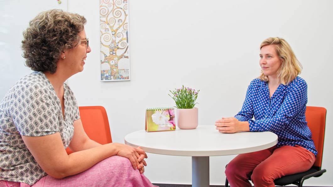 Teilnehmerin und Integrationscoach reden miteinander an einem runden Tisch