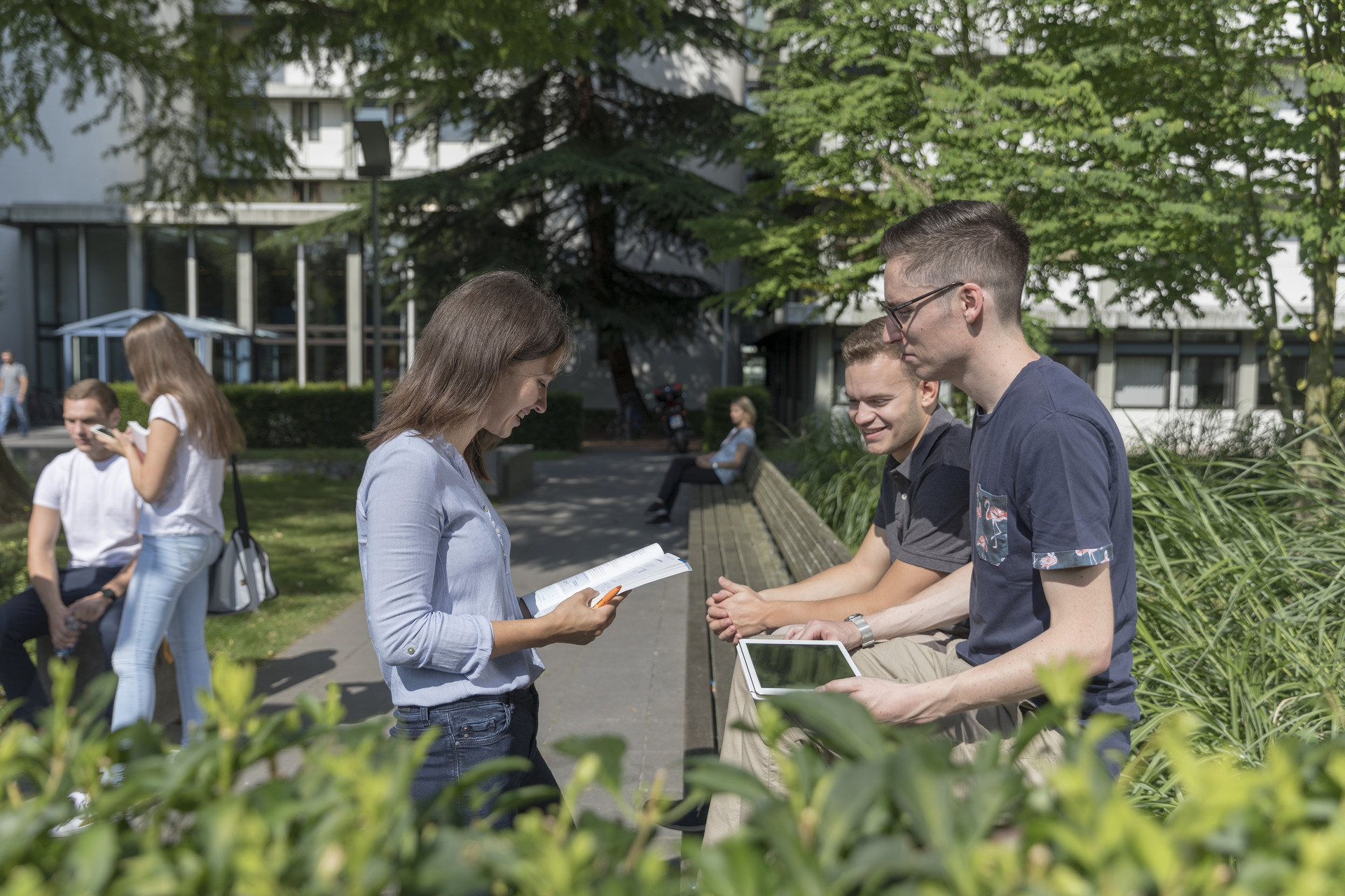 Einige Teilnehmende stehen zusammen und sprechen Gruppen stehen zusammen auf dem Campus vor Internat.