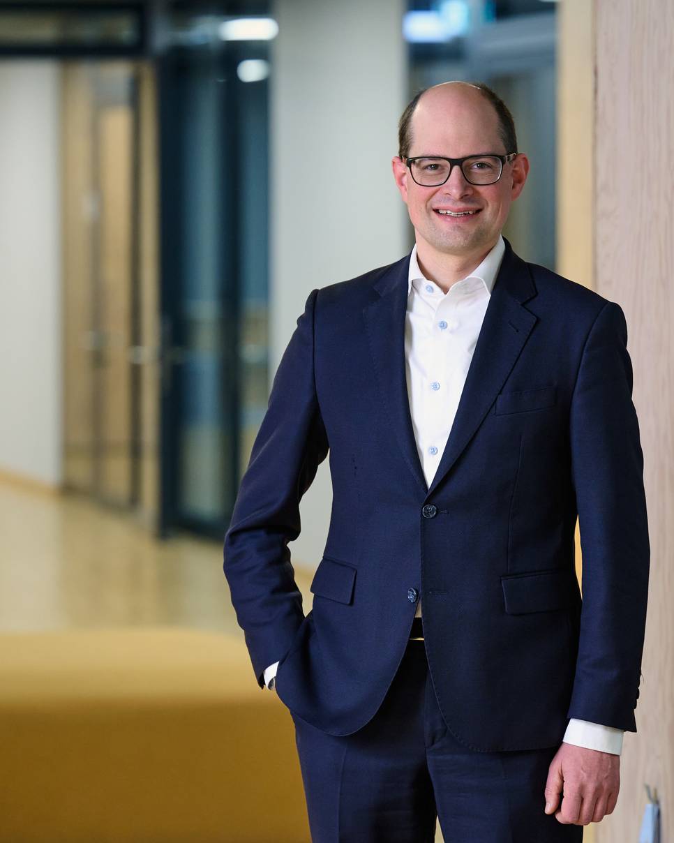 Stefan Medinger steht in einem blauen Anzug in einem Bürogebäude